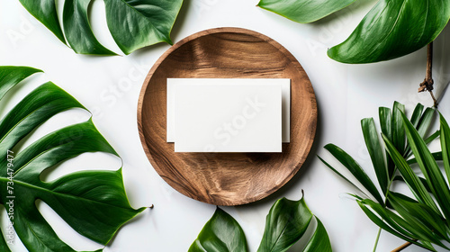 Modern mock up, 2 blank business cards on a wooden plate, decorated with aralia and monstera leaves on white background. corporate identity templates with a tropical touch. photo