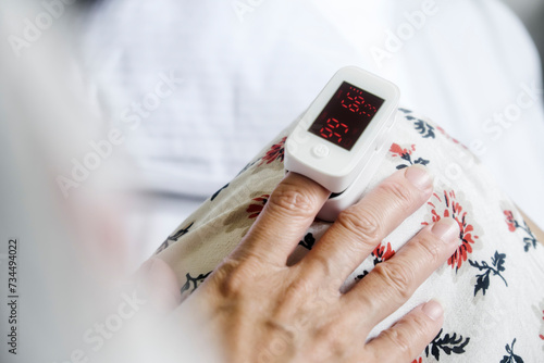 Closeup of hand of a woman using pulse oximeter to read blood flow at home. photo