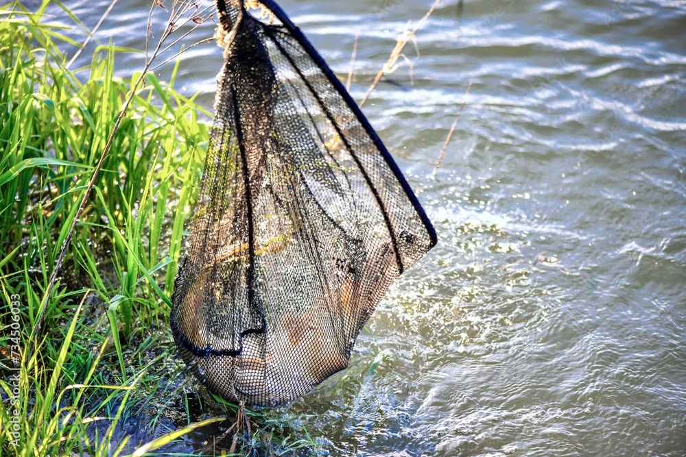 Fragment of fishing on a lake with clouds reflected in the water