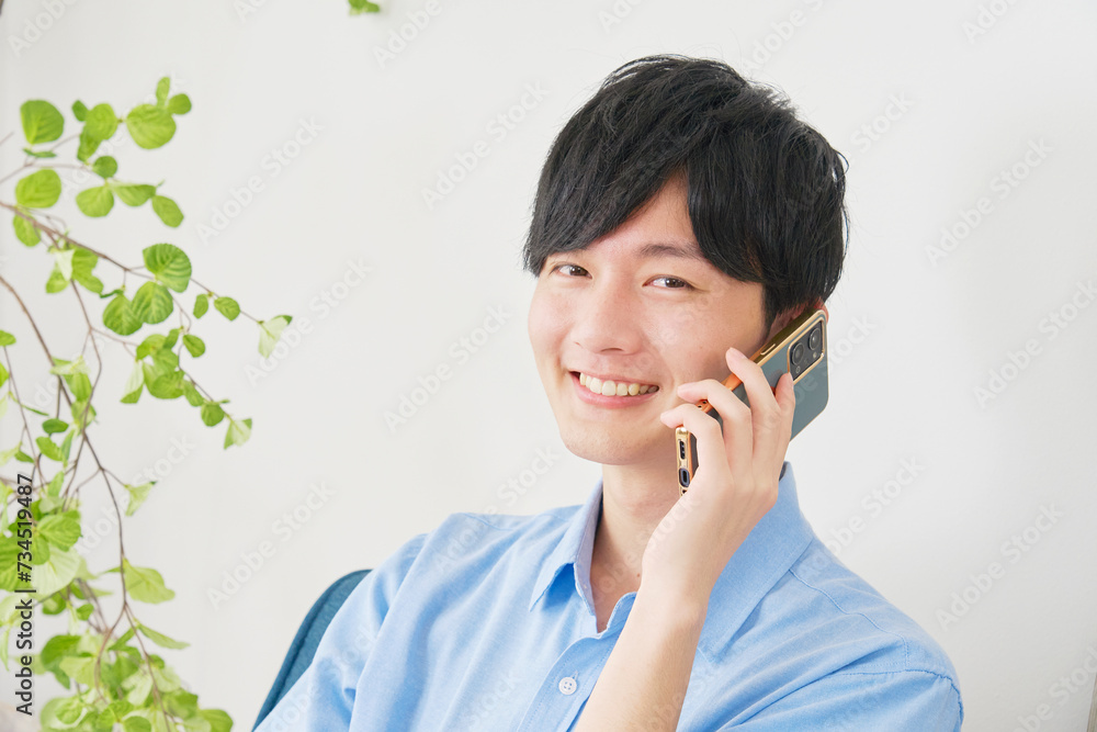 リビングでスマートフォンで電話をする男性　カメラ目線