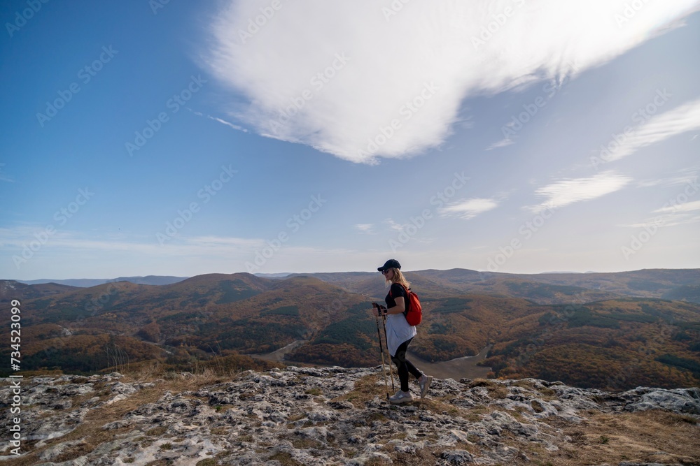 woman on mountain peak looking in beautiful mountain valley in autumn. Landscape with sporty young woman, blu sky in fall. Hiking. Nature
