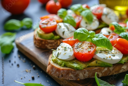 Close up of an open avocado sandwich on sourdough bread with cherry tomatoes mozzarella basil olive oil and oregano on a board