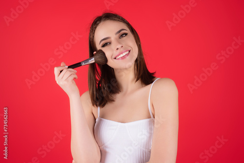 Beautiful young woman apply powder on face. Beauty Makeup. Portrait of female model with cosmetic brush. Perfect soft skin and natural makeup. Applying powder blush highlighter, foundation tone.