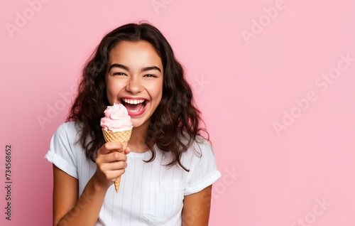 Summer portrait of happy young woman eating ice cream wearing sunglasses on pink background.