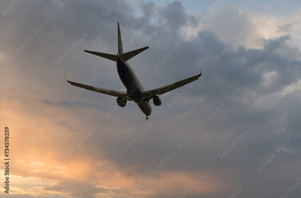 Fototapeta premium Silhouette of a civilian aircraft in a sunrise or sunset sky with beautiful clouds. 