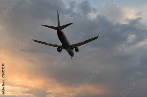 Silhouette of a civilian aircraft in a sunrise or sunset sky with beautiful clouds. 