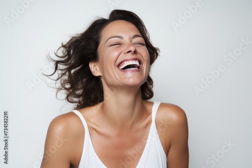 Portrait of a beautiful young woman laughing with closed eyes on gray background