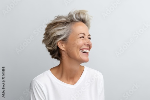 Portrait of happy senior woman with short grey hair laughing and looking up.