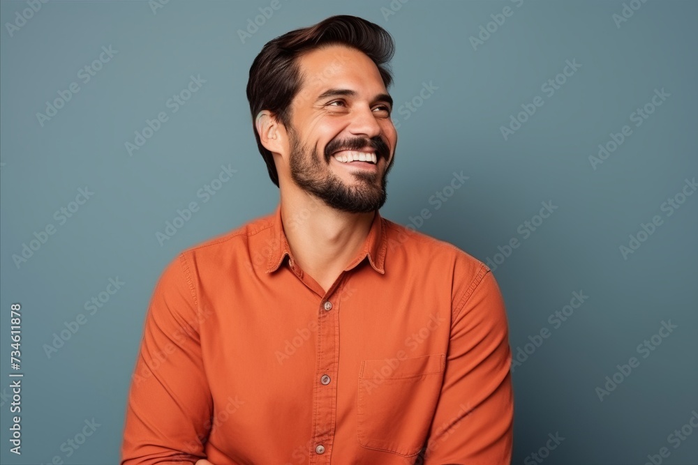 Portrait of a handsome young man laughing and looking at camera against blue background Portrait of a handsome young man laughing and looking at camera against blue background