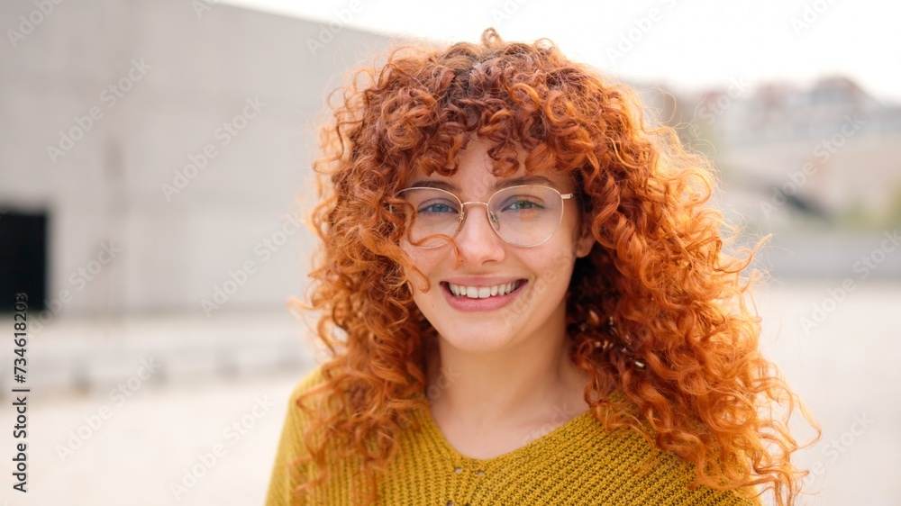Redhead woman with curly long hair smiling at camera Redhead woman with curly long hair smiling at camera