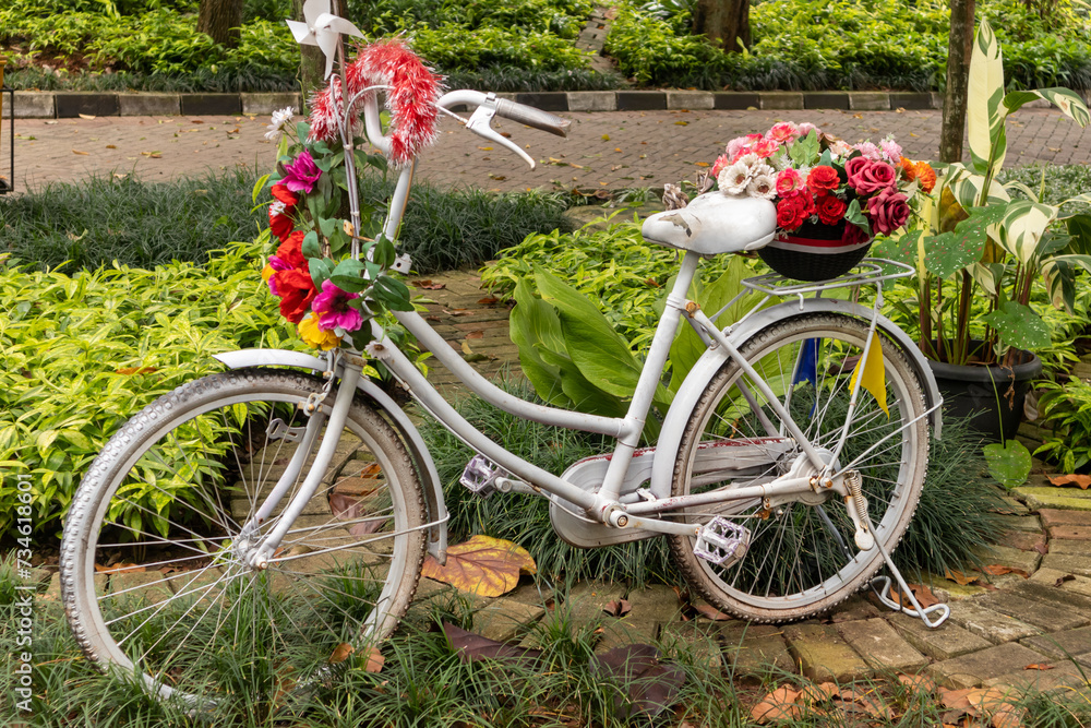 An old white vintage bicycle decorated with flowers in a park