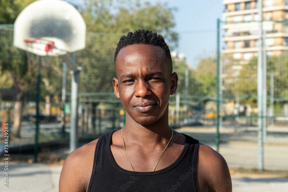 Headshot portrait of black young man in basketball court outdoors looking at camera. Headshot portrait of black young man in basketball court outdoors looking at camera.