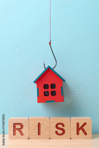 A red house suspended on a fishing hook above the 'RISK' blocks