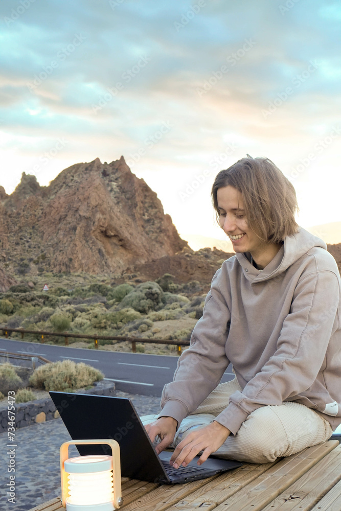 Young Man Working on Laptop Atop Van Roof in Teide Mountain at Dusk Young Man Working on Laptop Atop Van Roof in Teide Mountain at Dusk