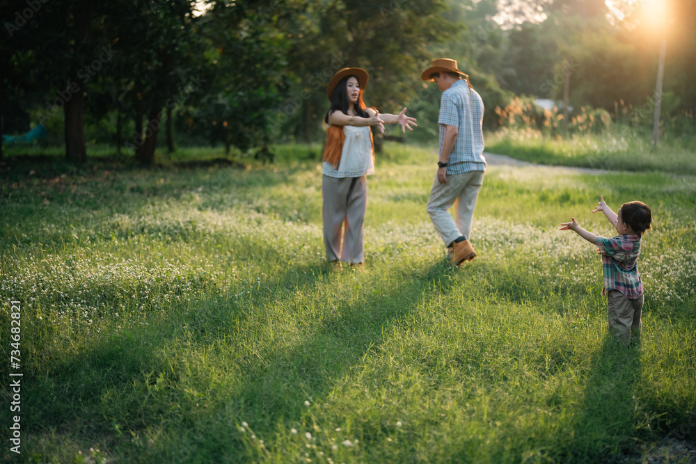 Fototapeta premium happy harmonious Asian family outdoors concept, Asian mother and son have activities happy fun together on holidays, grass land with sunlight