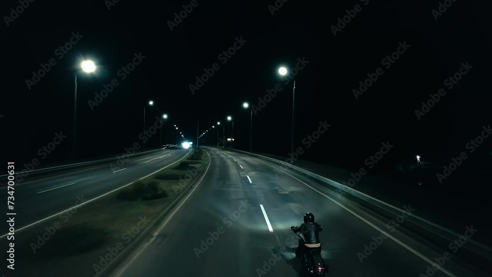 Aerial view of biker in black helmet on night highway with dividing strip Aerial view of biker in black helmet on night highway with dividing strip