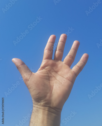 Hand shaking in air with blue sky background in sun light. 