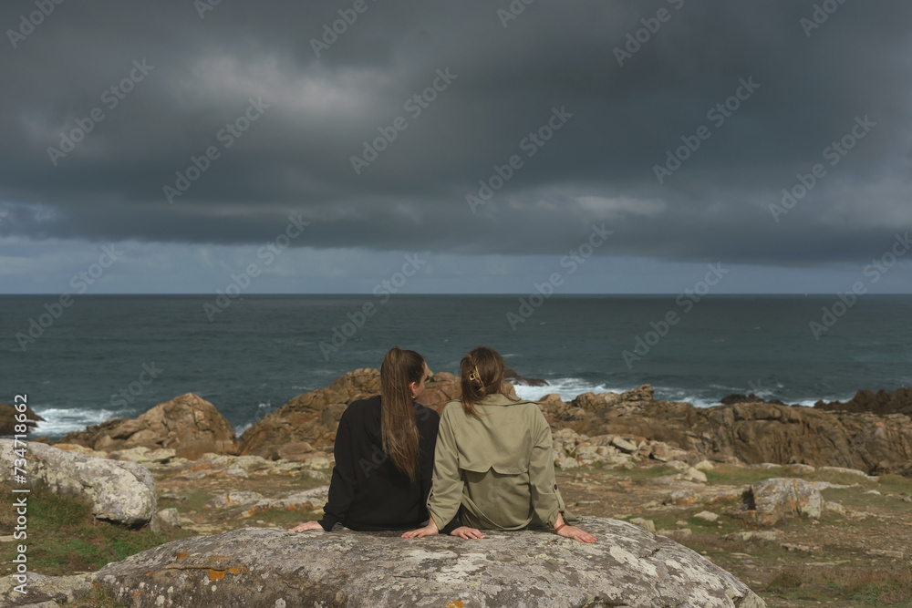 Two young women looking towards the ocean in Corrubedo, Ribeira.
