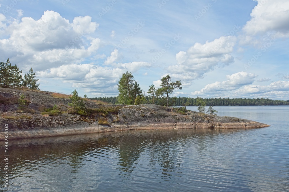 Rocky lake shore and reflection on water surface in cloudy summer weather. Rocky lake shore and reflection on water surface in cloudy summer weather.