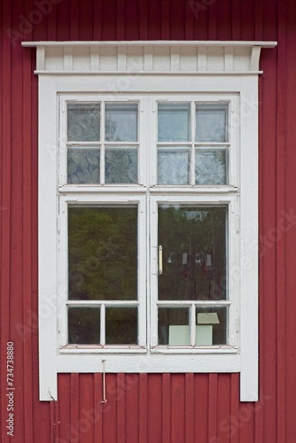 White framed window on old red painted wooden wall.