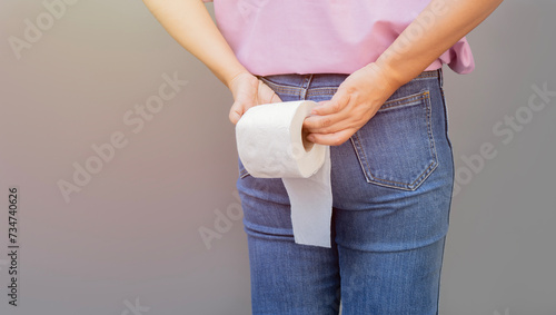 Woman hand holding her bottom and tissue or toilet paper roll. Disorder, Diarrhea, Constipation. photo