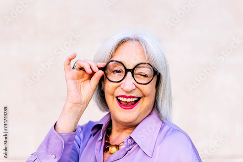 Φωτογραφία portrait of nice senior woman in glasses smiling and winking looking at camera,