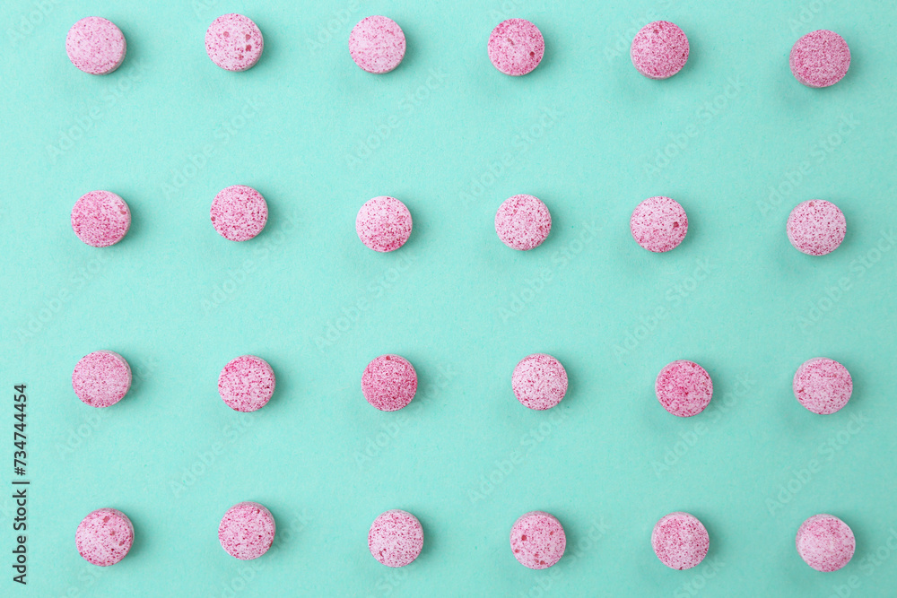 Many pink vitamin pills on turquoise background, flat lay Many pink vitamin pills on turquoise background, flat lay