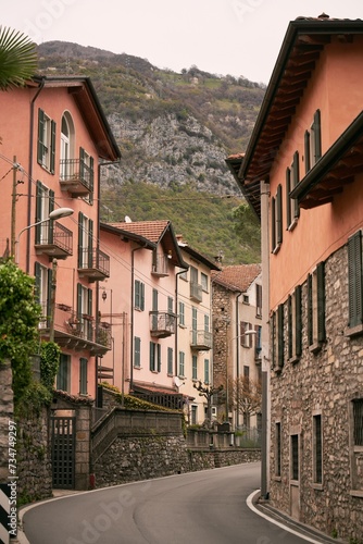 A narrow and historic street in Italy with stone houses. The facades and windows of the houses are varied and colorful
