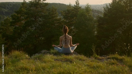 Wallpaper Mural Young woman practicing yoga at sunset in a beautiful mountain location. Torontodigital.ca