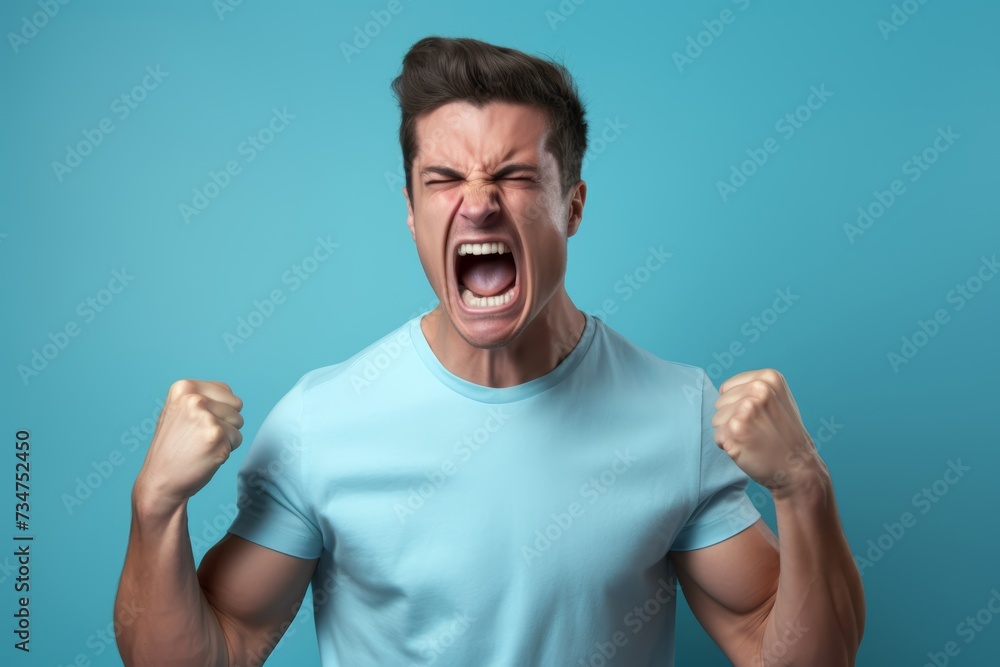 27-year-old Caucasian man, his face contorted in anger, fists clenched, expressing aggression due to a heated argument, set against a solid pastel blue background. 27-year-old Caucasian man, his face contorted in anger, fists clenched, expressing aggression due to a heated argument, set against a solid pastel blue background.