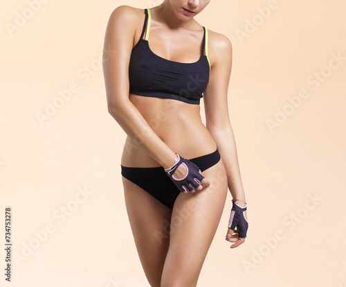 Attractive young woman with a perfect body in black lingerie posing against a light background. Fitness class.