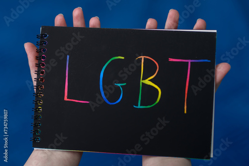 Tęczowy napis LGBT trzymany na kartce w dłoniach  © Paweł Kacperek