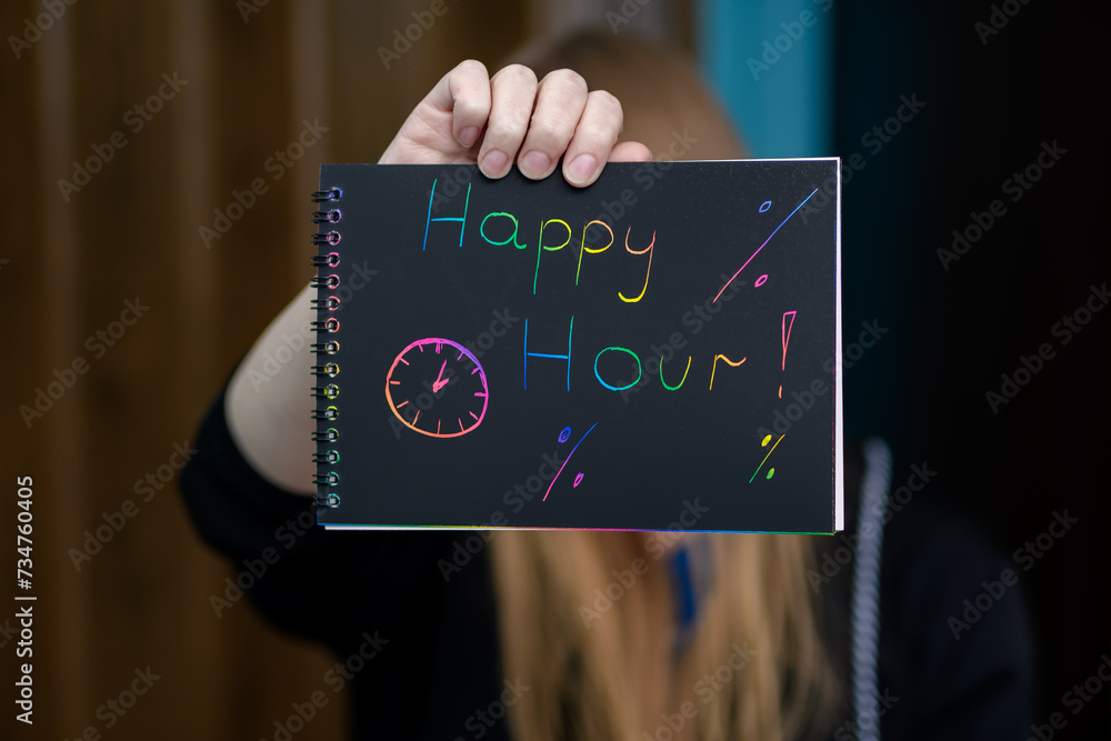 Kobieta trzyma w dłoniach reklamę infkrmujaca o happy hour, napis na kartce - obrazy, fototapety, plakaty 
