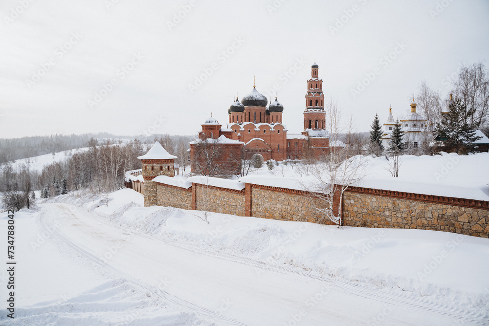 Winter landscape with Russian Orthodox monastery in snow-covered hills and forests