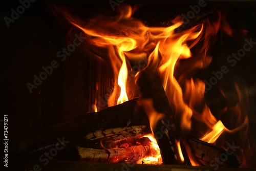 Bonfire with burning firewood on dark background, closeup