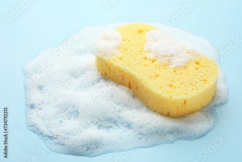Yellow sponge with foam on light blue background