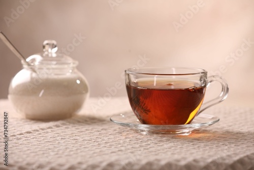 Aromatic tea in cup, saucer and sugar on table