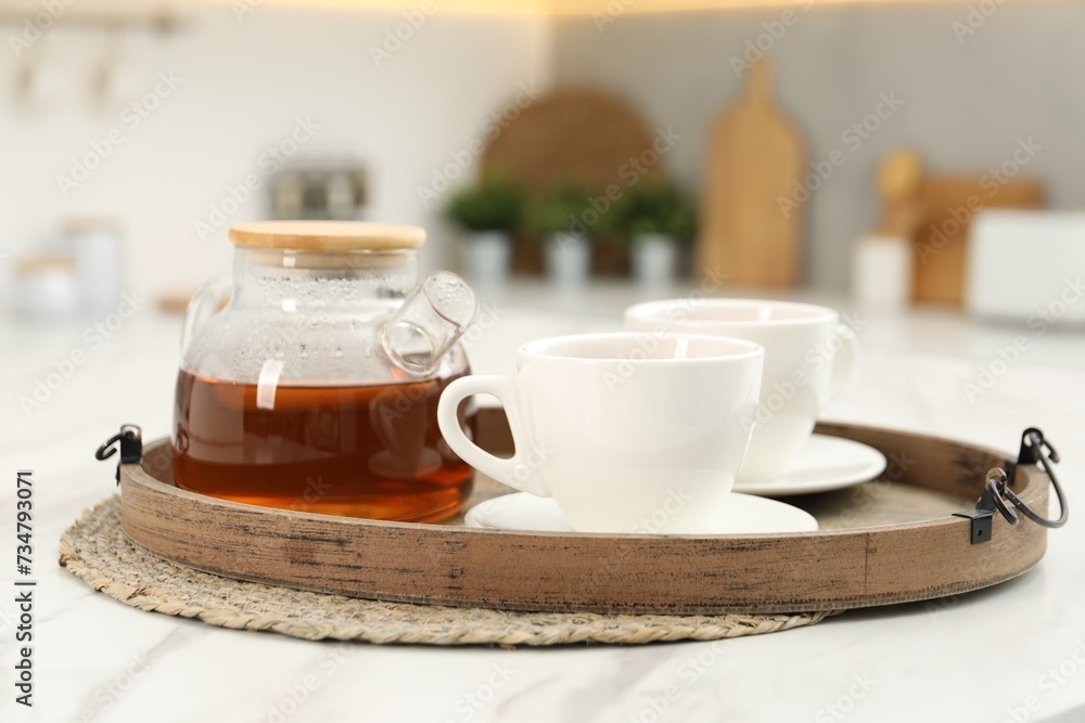 Aromatic tea in glass teapot and cups on white table