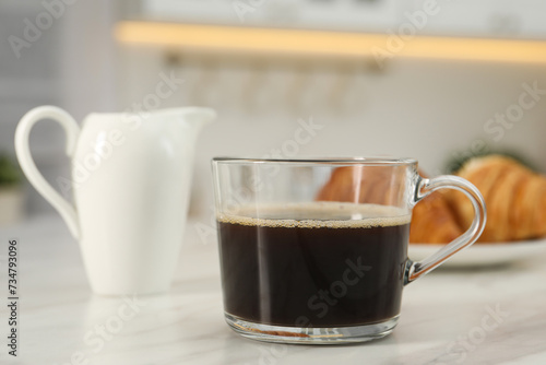 Aromatic coffee in glass cup on white marble table