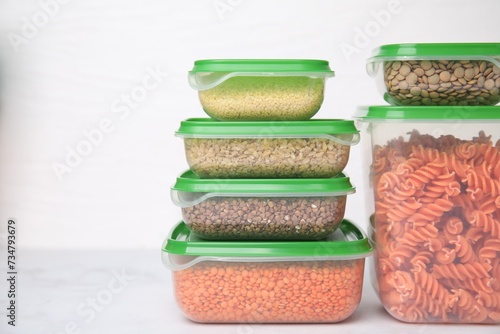 Plastic containers filled with food products on white table. Space for text