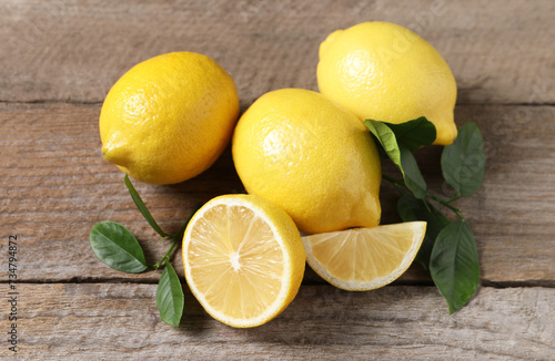 Fresh lemons and green leaves on wooden table  closeup