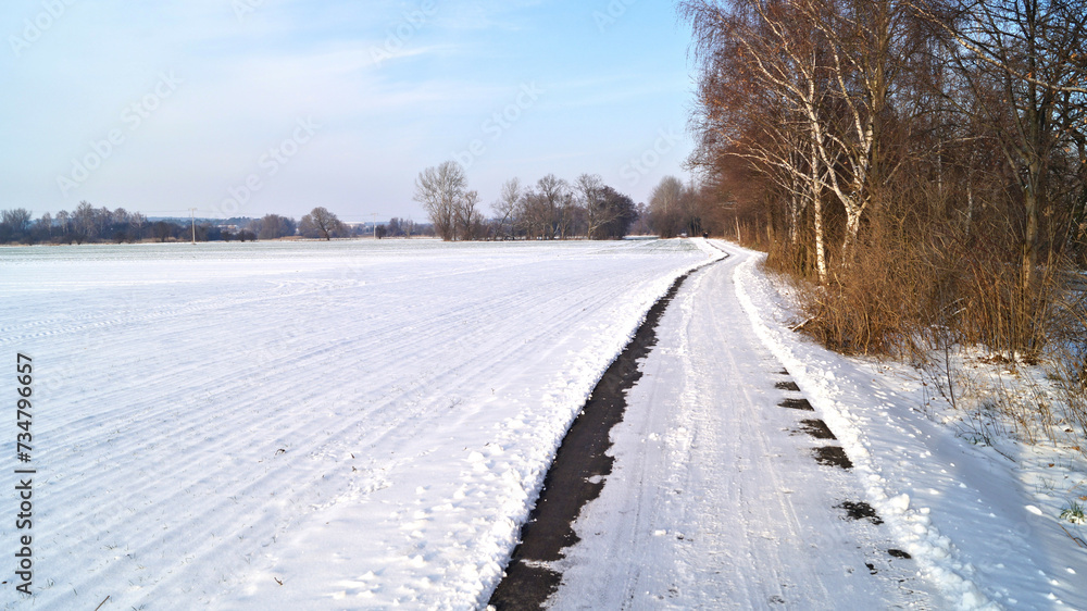 Radweg am schneebedeckten Feld