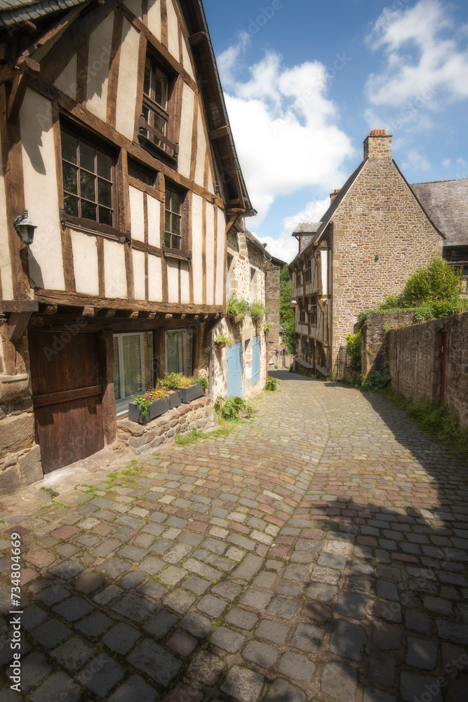 Vieille rue pavée dans le centre historique de Dinan en Bretagne, la rue du petit fort, vue verticale, sous un ciel bleu ensoleillée Vieille rue pavée dans le centre historique de Dinan en Bretagne, la rue du petit fort, vue verticale, sous un ciel bleu ensoleillée