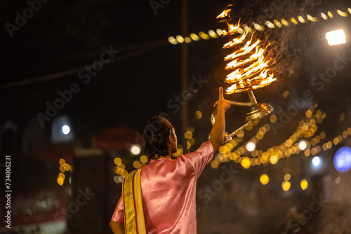 Ganga aarti, Portrait of young priest performing holy river ganges evening aarti at dashashwamedh ghat in traditional dress with hindu rituals. photo