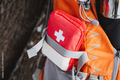 Red and white first aid kit attached to backpack, ideal for travel, hiking, camping. photo