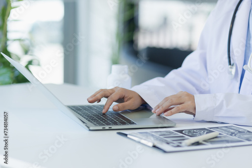 Asian female doctor working with laptop and health personal data in modern clinic, Healthcare and medical concept.