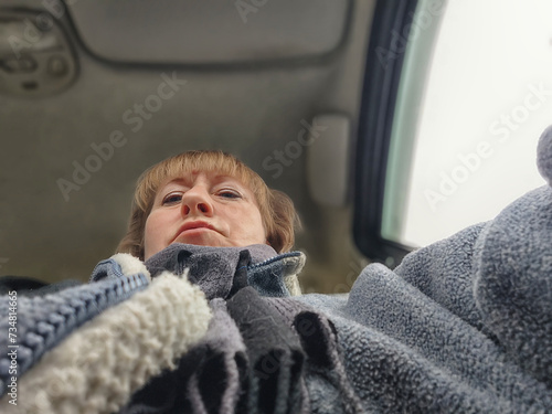 A funny cute blonde girl or a middle-aged woman driving a car in summer, autumn, spring day. A female driver on a solo trip
