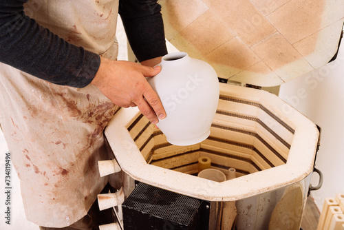 Bild auf Leinwand Crop of male artisan hands putting clay vase into electric kiln