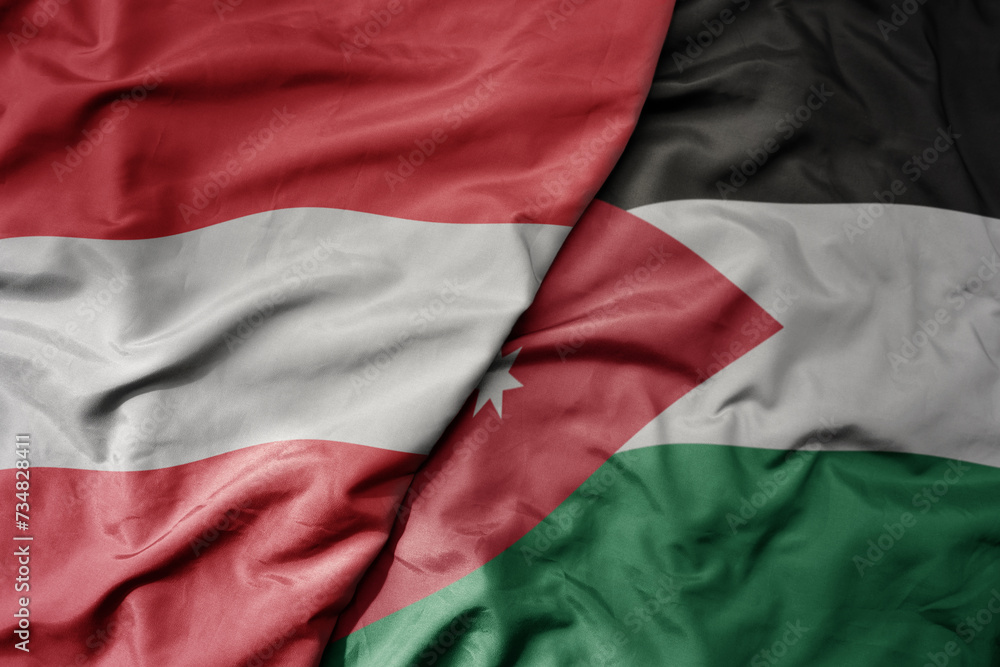big waving national colorful flag of jordan and national flag of austria .