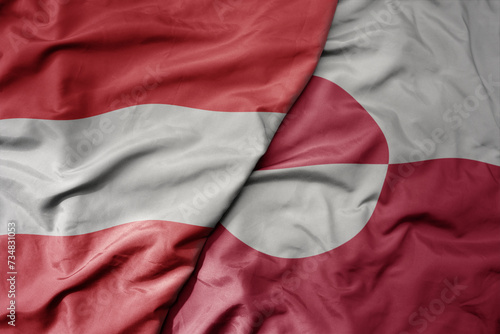 big waving national colorful flag of greenland and national flag of austria .